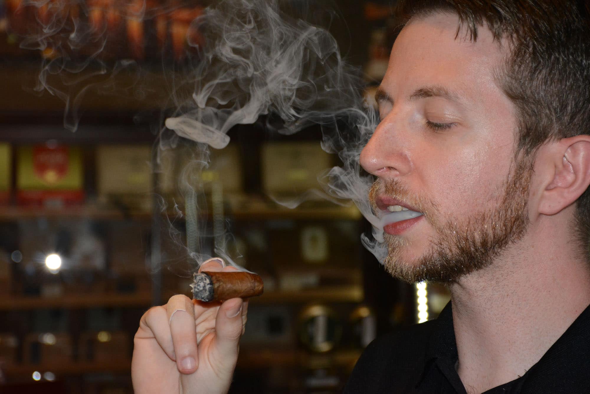 Kelsey Sims, Davidus Cigars sales associate, samples the wares.