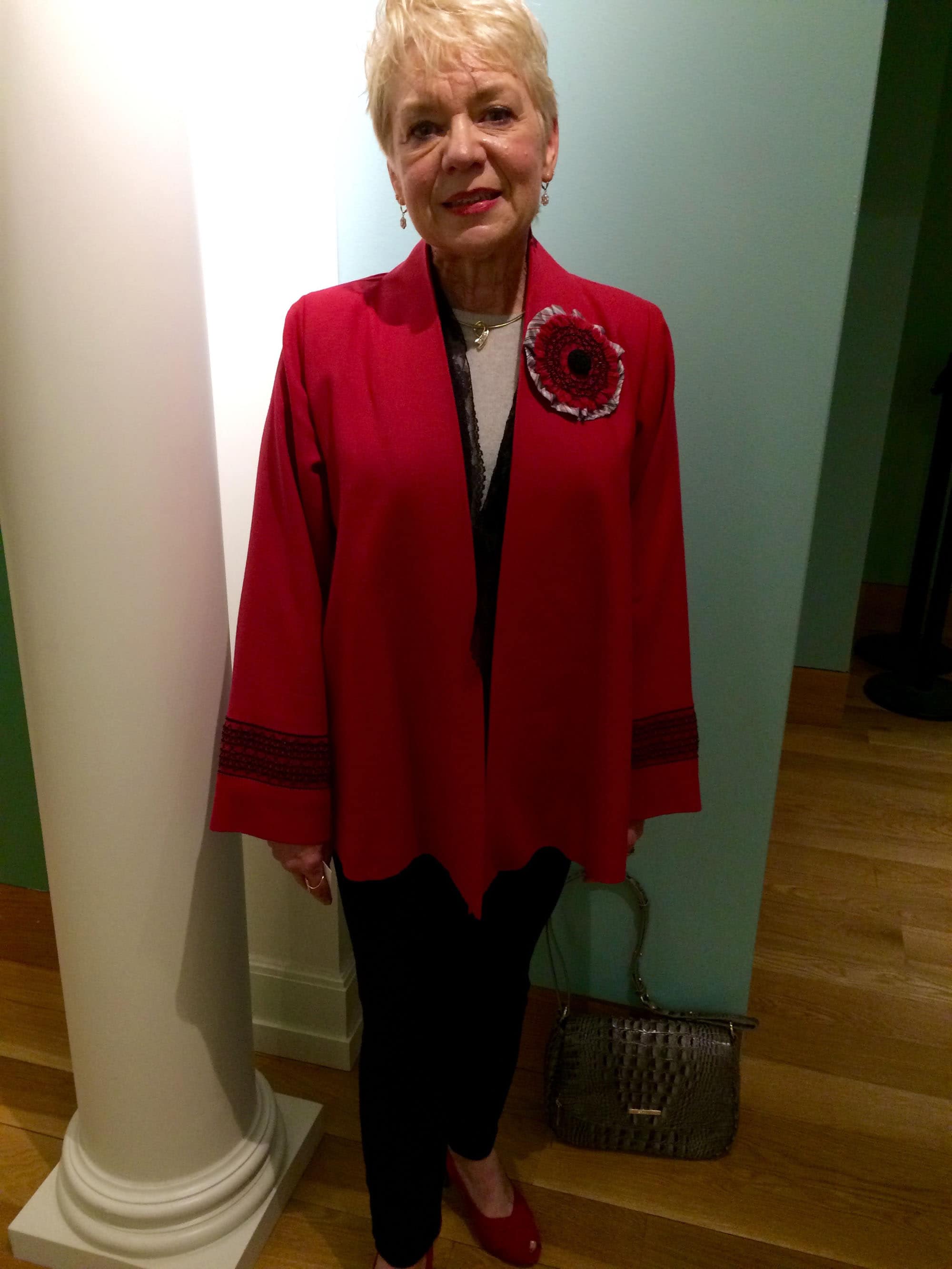 Barbara Meger, a seamstress with Classic Creations, showing off a red felt jacket of her own design with hand-stitched smocking and rosette