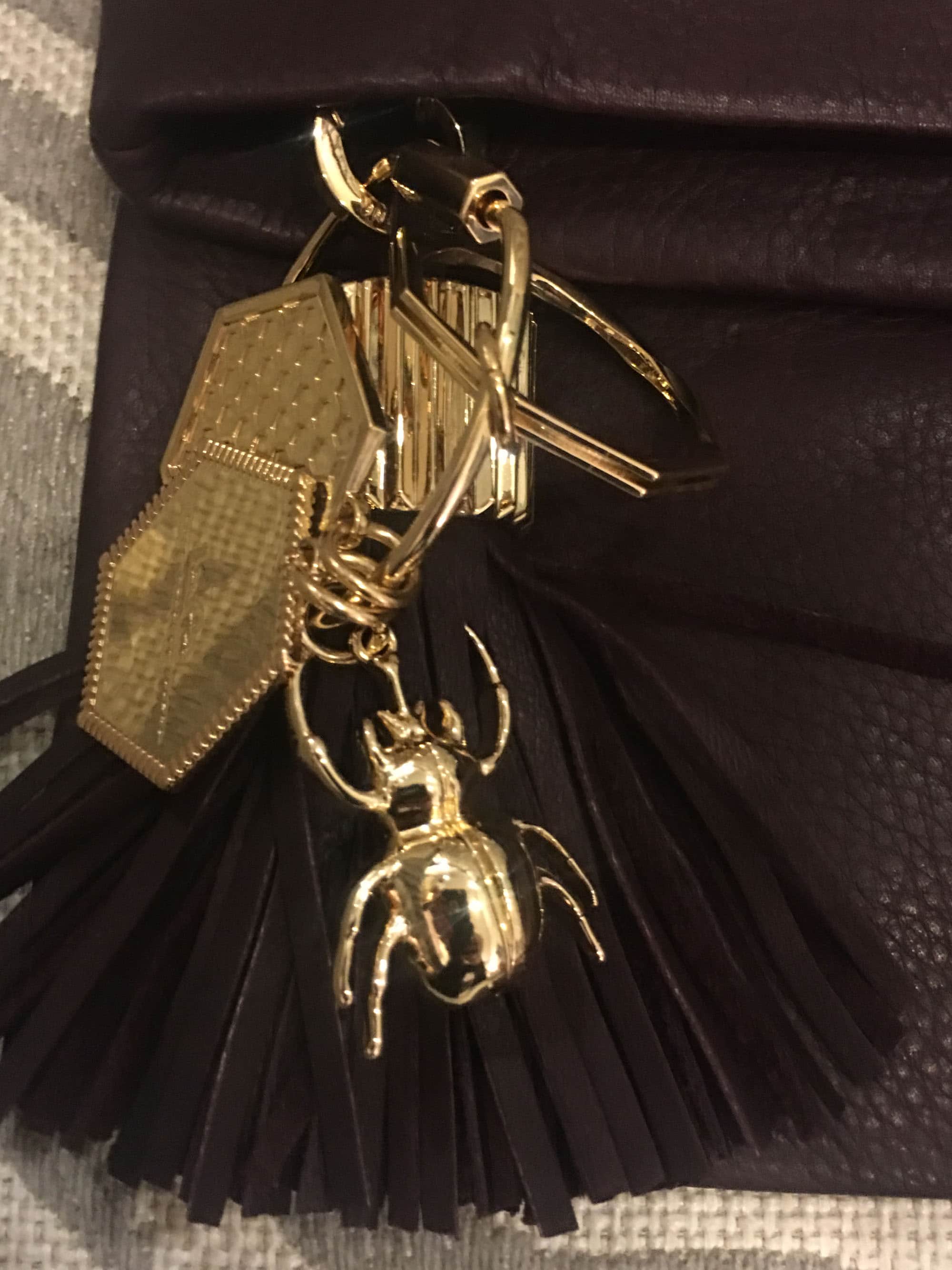 She added some statement pieces to finish her look: dark burgundy leather clutch with a tassel and added beetle charm...
